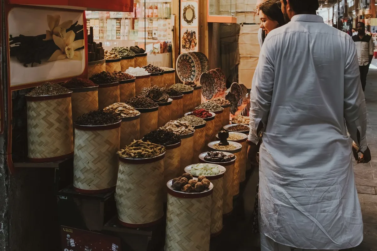 A man and woman are shopping for food in a market with a variety of items on display.