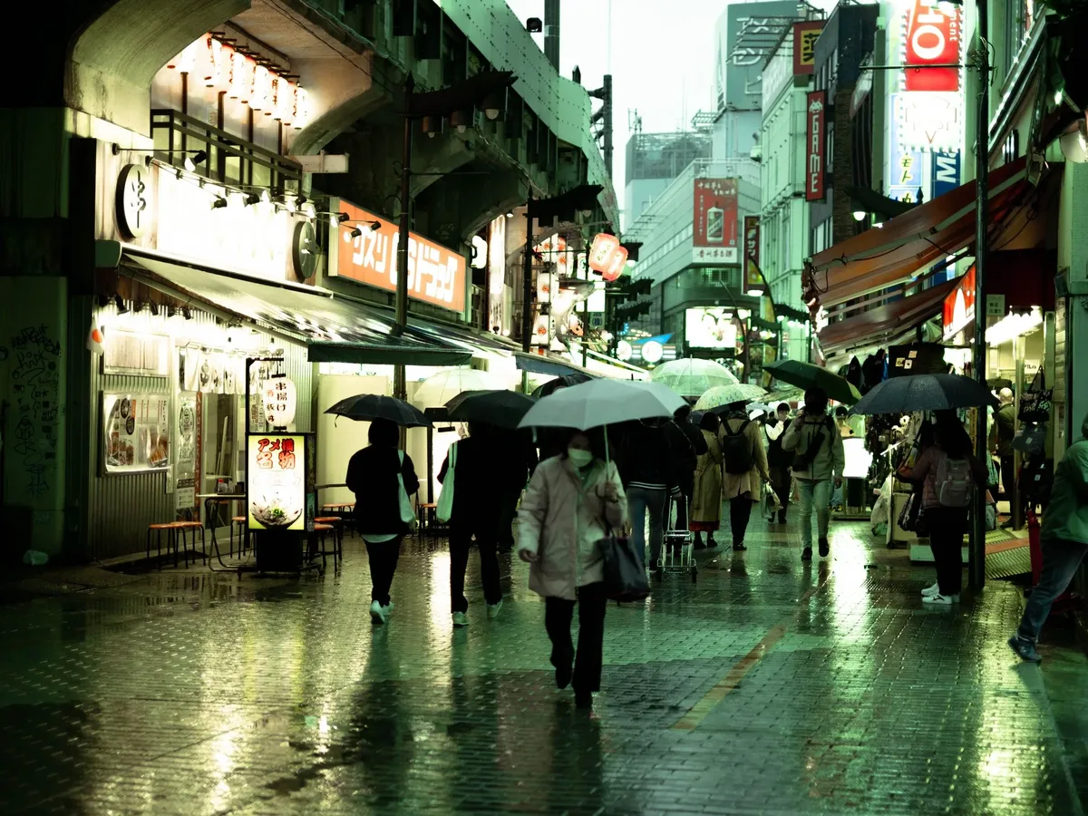 A busy city street with people walking and holding umbrellas.