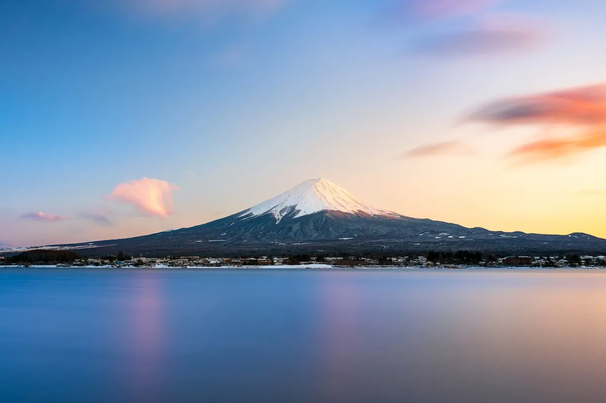A beautiful sunset over a body of water with a mountain in the background.