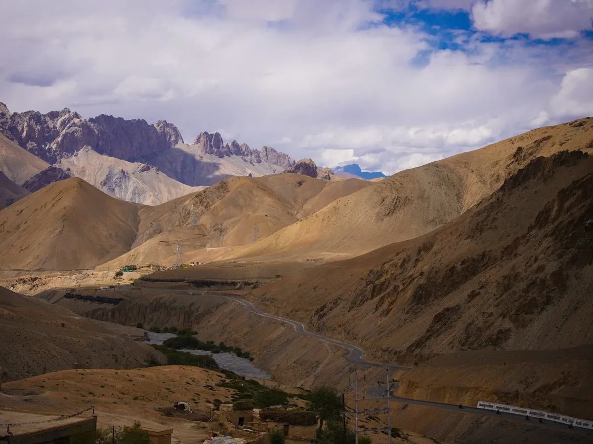 A mountainous area with a dirt road and a train in the distance.