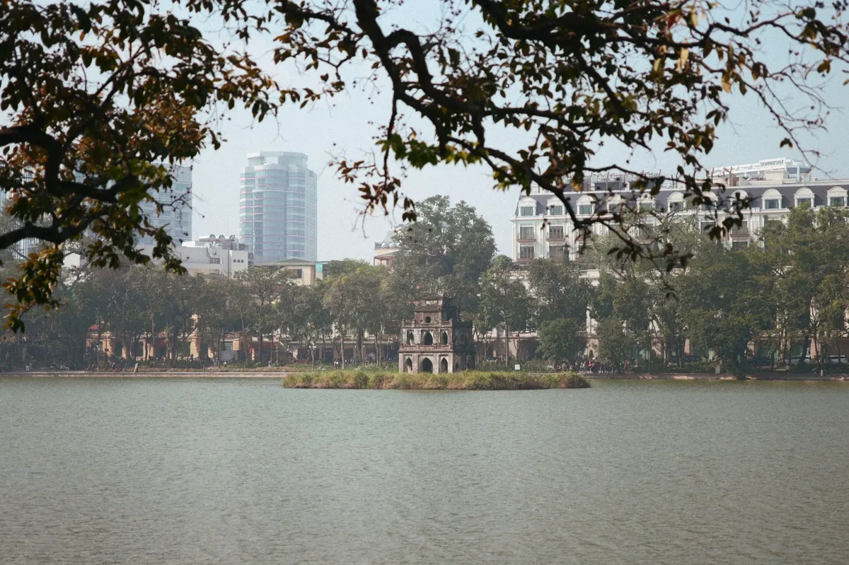 A city skyline is visible in the distance, with a small island in the middle of a lake.