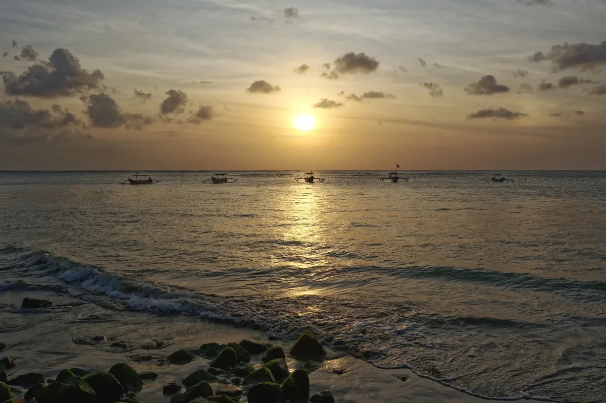 A beautiful sunset over the ocean with boats in the water.