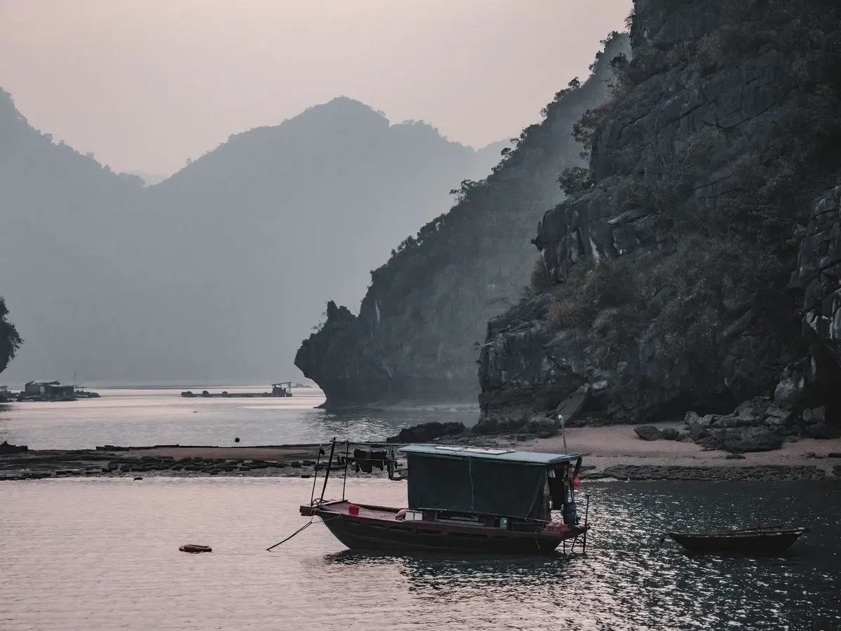 A boat is docked in a bay with a mountain in the background.