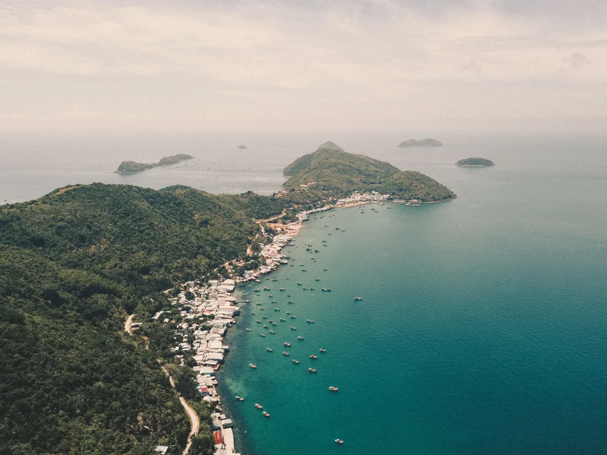 A beautiful island with a mountain in the background and a small village on the shore.