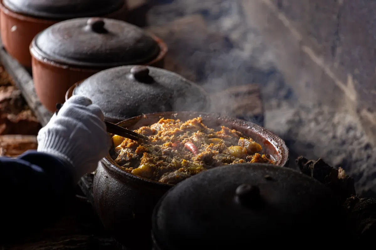 A person is cooking food in a pot on a stove.