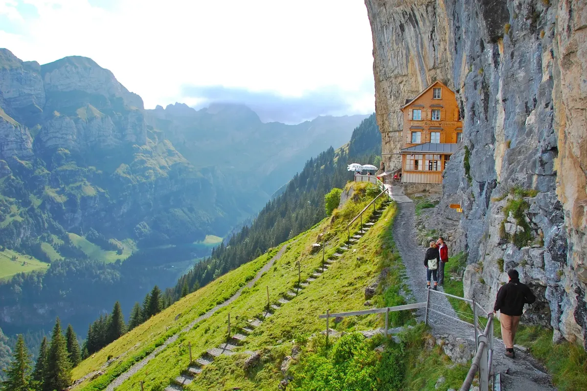 A mountain path along a green hillside below a cliff in Appenzell