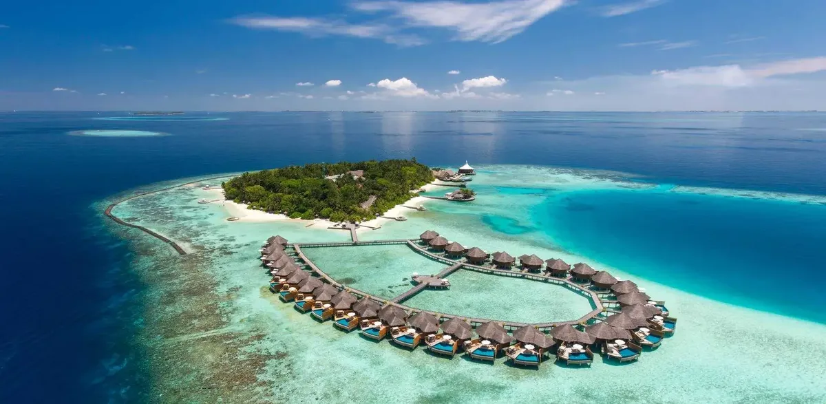 A small resort island ringed by overwater villas and a turquoise reef