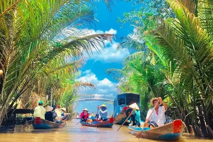 Rowing boats with visitors on a palm-lined canal in the Mekong Delta