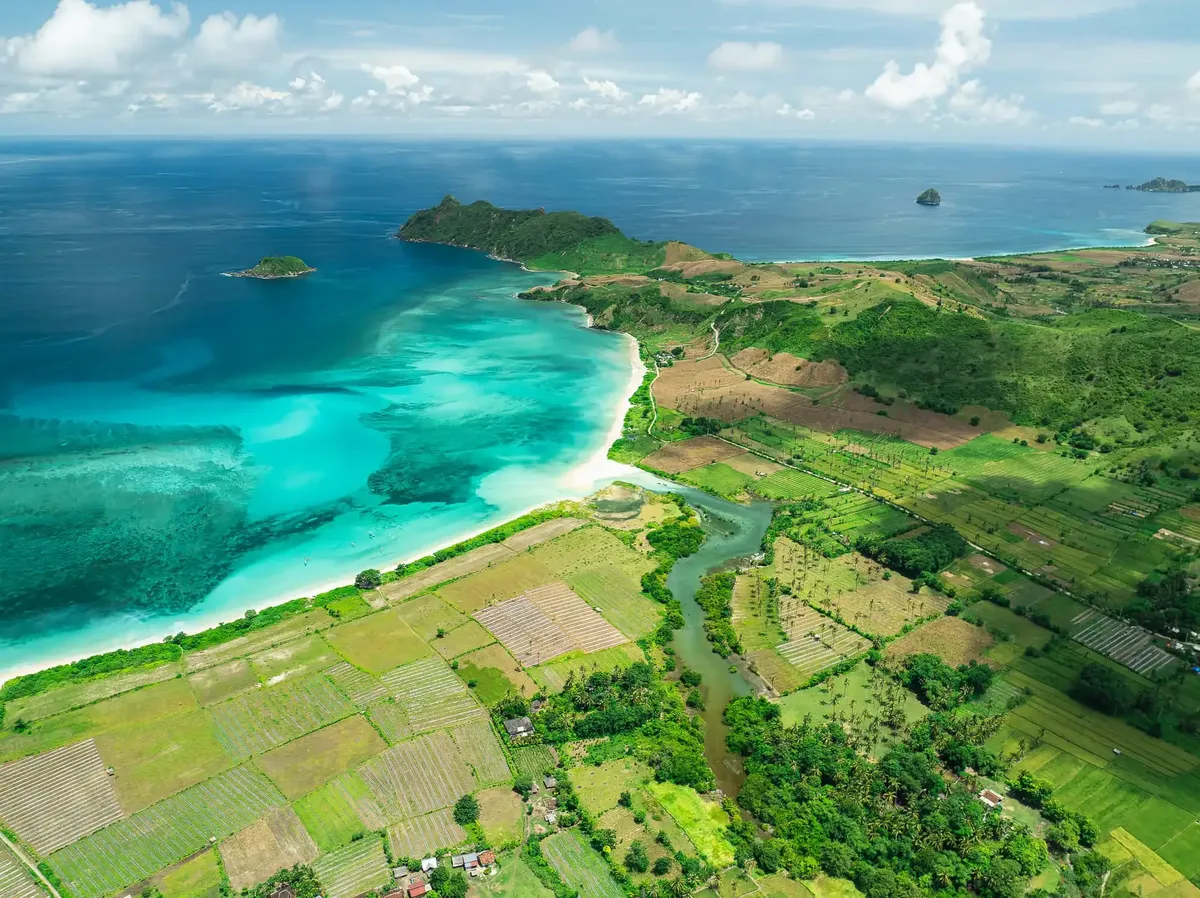 A turquoise bay and green fields on the coast of Lombok, from the air