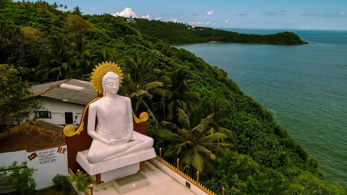 A white Buddha statue on a hilltop above the sea in Sri Lanka