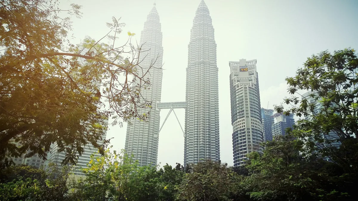 The Petronas Twin Towers rising above trees in Kuala Lumpur