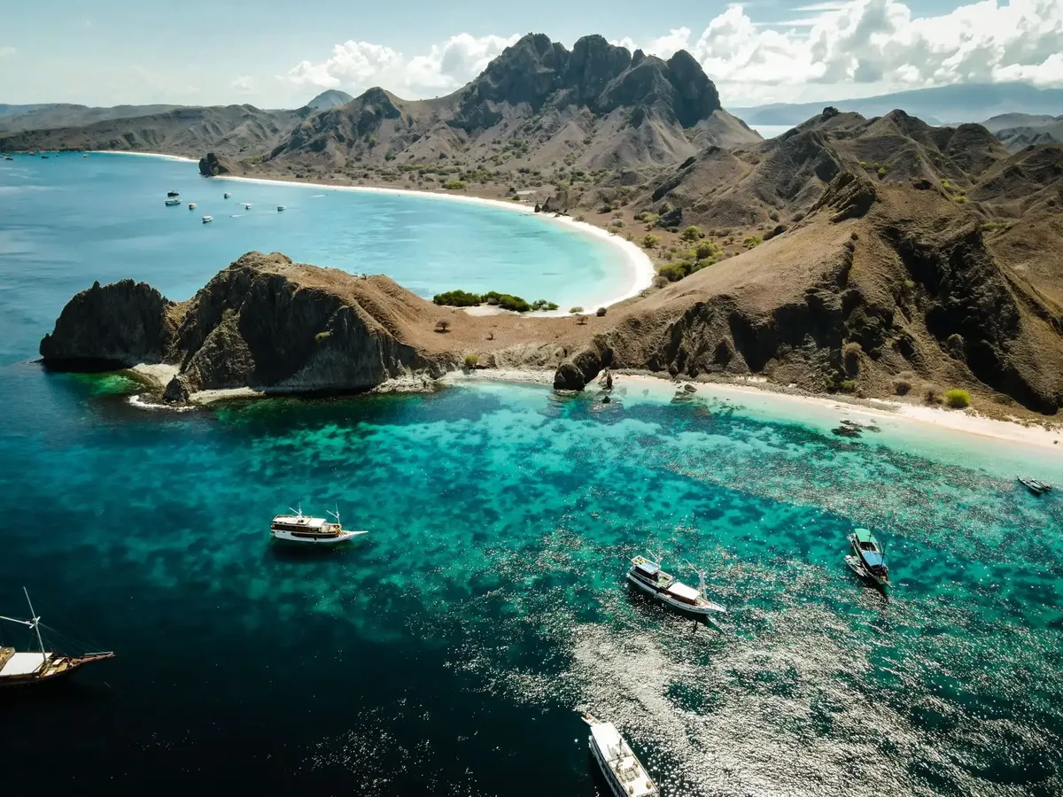 Bays and bare ridges of an island in Komodo National Park, with boats at anchor