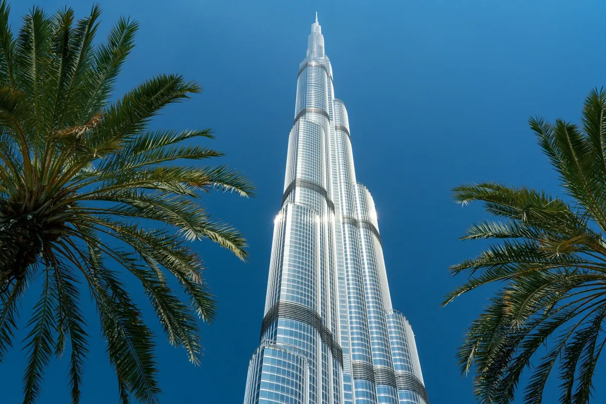 The Burj Khalifa against a blue sky, framed by palm trees