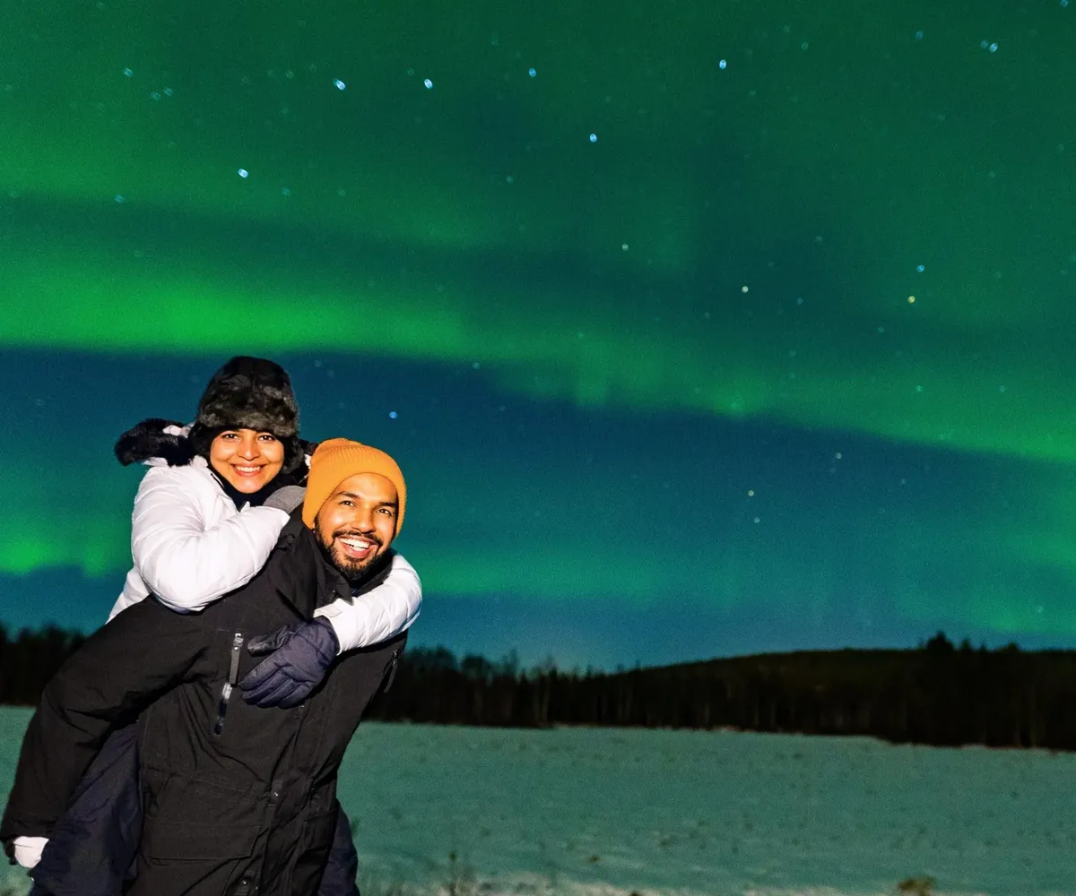 A couple in a snowy field with a green sky above them.